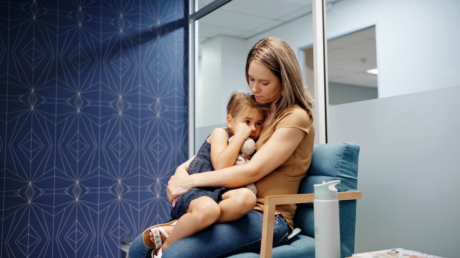 Medical group goes against CDC, recommends COVID shots for young kids Woman with sick daughter.jpg